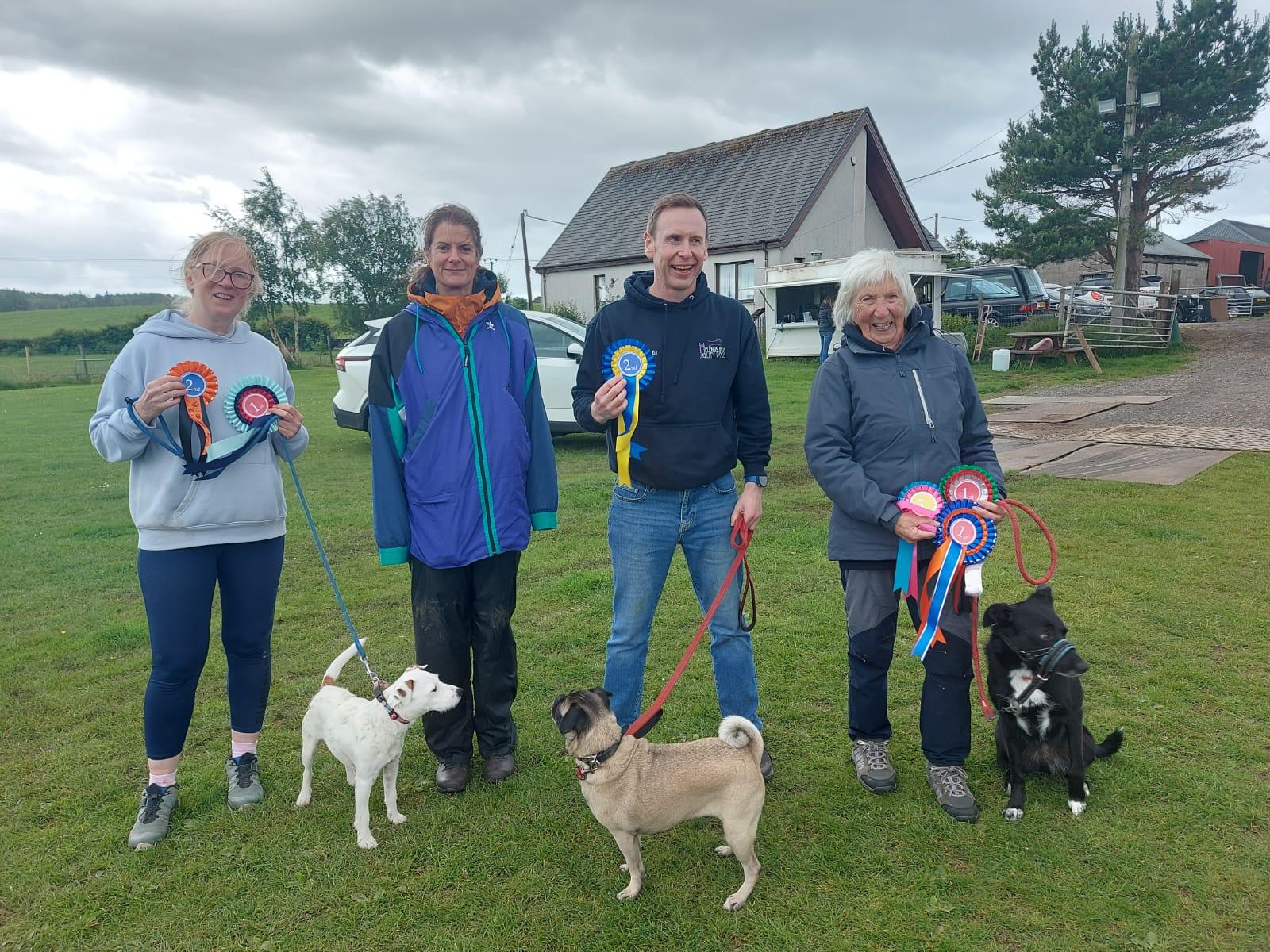 Handlers and dogs with competition rosettes